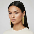 Woman wearing gold earrings against a plain background