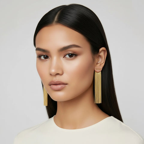 Woman wearing gold earrings against a plain background