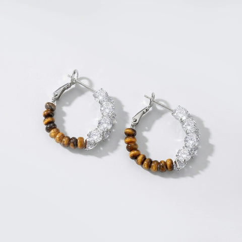Pair of hoop earrings with wooden beads and clear stones on a light gray background