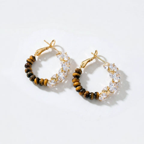 Pair of hoop earrings with gold, clear, and brown beads on a white background