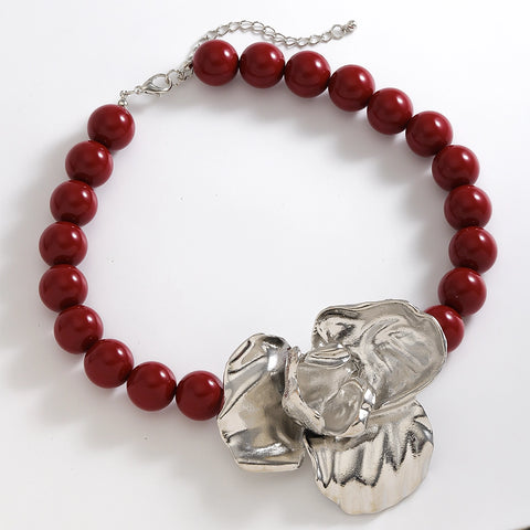 Bracelet with red beads and a silver elephant charm on a white background