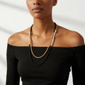 Woman wearing a black and gold necklace against a white background