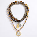 A multi-strand beaded and chain necklace set displayed on a clean white background. The set features brown tiger's eye beads, silver-toned chains, black beads, and translucent pastel beads in purple, orange, and yellow.