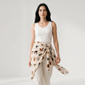 Woman wearing a white tank top and a patterned skirt with a plain background