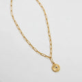 Gold chain necklace with a small pendant on a light gray background