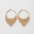 A pair of gold hoop earrings with a triangular mesh of clear rhinestones, displayed on a light gray background.