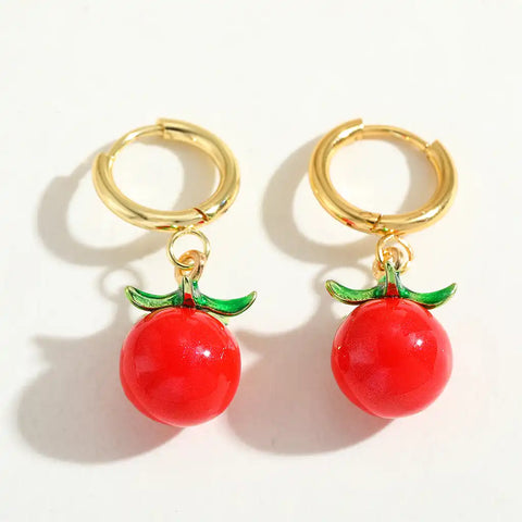Gold hoop earrings with red apples droplets on a white background