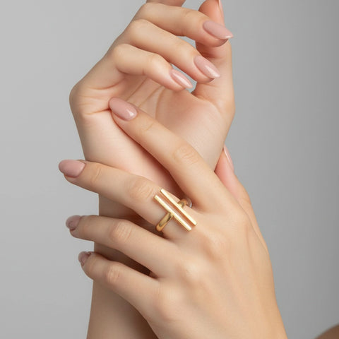 Close-up of a hand wearing a gold ring on a neutral background