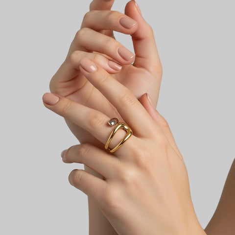 Gold ring with a small gemstone on a hand against a plain background