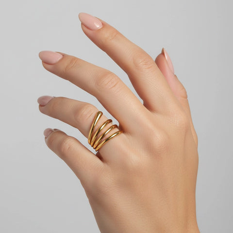 Hand wearing a gold ring on a plain background