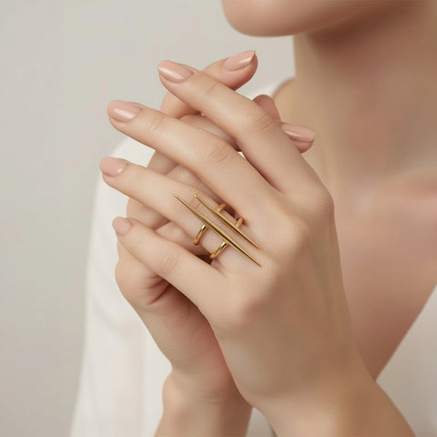 Close-up of a hand wearing a gold ring on a neutral background