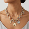 Necklace with gold and silver charms worn by a person on a neutral background