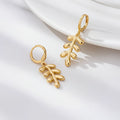 Gold leaf-shaped earrings on a white surface