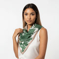 Woman wearing a green and white patterned scarf on a plain background