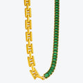 Gold chain necklace with green gemstones on a white background