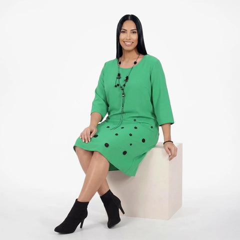Woman wearing a green dress with black polka dots on a white background