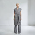 Woman wearing a gray textured dress with wide-leg pants on a white background