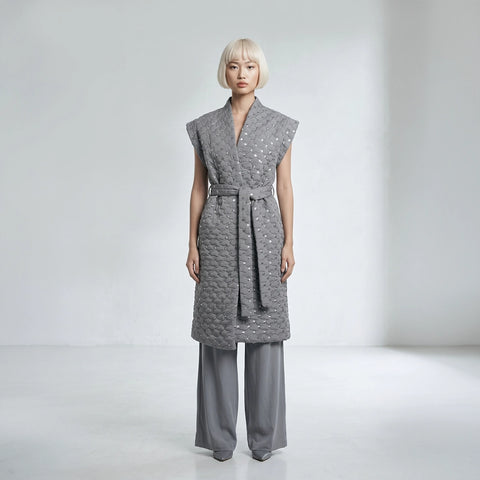 Woman wearing a gray textured dress with wide-leg pants on a white background