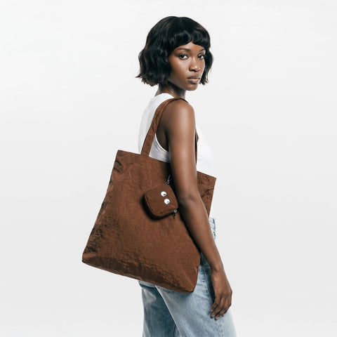 Woman holding a brown tote bag against a white background