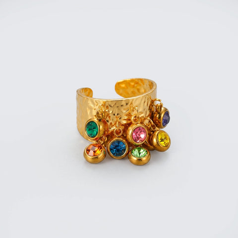 Gold ring with colorful gemstones on a light gray background