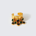 Gold cuff bracelet with green gemstones on a white background