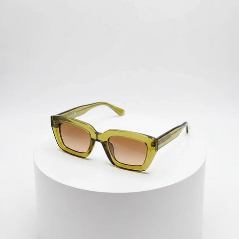 Green sunglasses with brown gradient lenses on a white pedestal against a white background