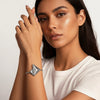 Woman wearing a silver bracelet on a plain background