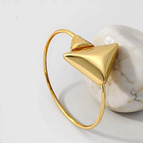Gold bracelet with a triangular design on a marble surface