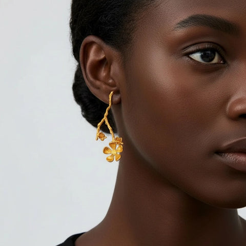 Close-up of a woman wearing gold floral earrings against a neutral background
