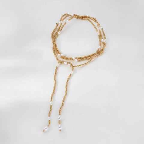 Gold and pearl necklace on a light gray background