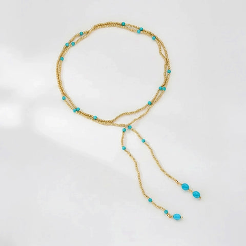 Gold necklace with turquoise beads on a white background