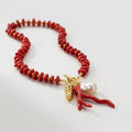 Red coral necklace with a pearl and gold clasp on a white background