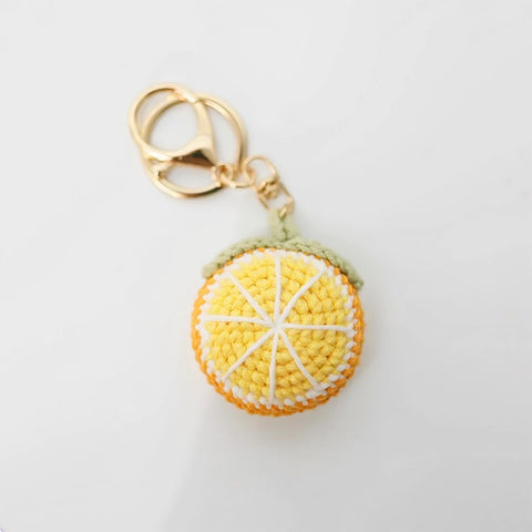 Crocheted lemon keychain with a gold ring on a light gray background