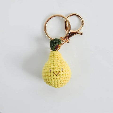 Crocheted pear-shaped keychain with a gold ring on a light gray background