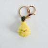 Crocheted pear-shaped keychain with a gold ring on a light gray background