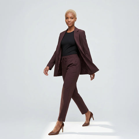Woman wearing a brown suit with a black top on a white background
