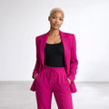 Woman wearing a bright pink suit with a black top on a white background