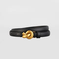 Black leather bracelet with a gold knot clasp on a light gray background