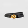 Black leather bracelet with a gold knot clasp on a light gray background