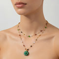 Necklace with a green pendant on a mannequin against a neutral background