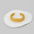 Gold bracelet on a white stone surface with a gray background