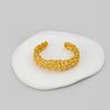 Gold bracelet on a white stone surface with a gray background