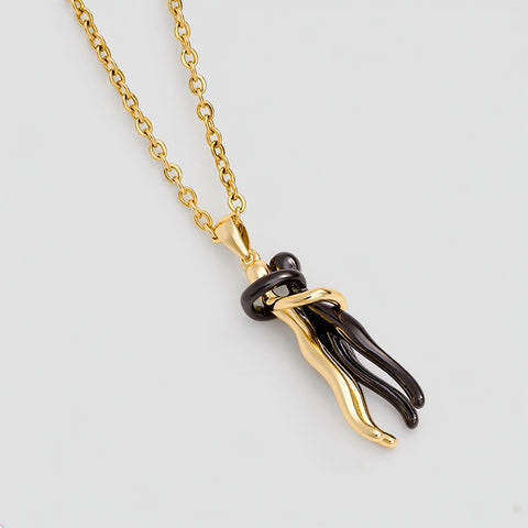 Gold and black pendant necklace on a light gray background