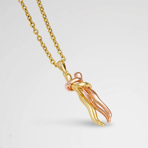 Gold and rose gold necklace with a unique pendant on a light gray background