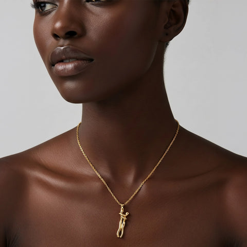Woman wearing a gold necklace with a pendant on a neutral background
