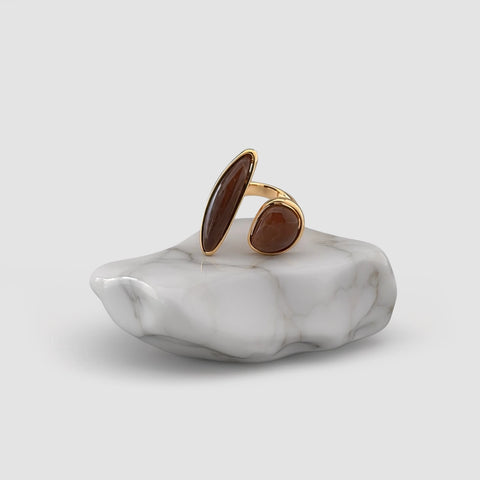 Gold ring with brown stones on a marble base against a white background