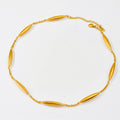 A gold chain necklace featuring seven elongated, polished oval links spaced evenly, displayed on a clean white background.