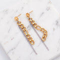 A pair of gold and silver drop chain earrings displayed on a white marble background.