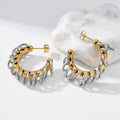 Gold-tone hoop earrings wrapped with silver ring accents, displayed on a white surface beside a marble stone.