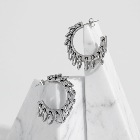 Gold-tone hoop earrings wrapped with silver ring accents, displayed on a white surface beside a marble stones.